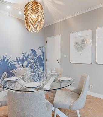 Sala de jantar com pavimento de madeira, paredes pintadas com tinta bege e molduras brancas e mobiliário 